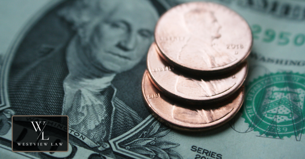 Three pennies stacked on a US dollar bill, representing the pay California workers lose to wage theft